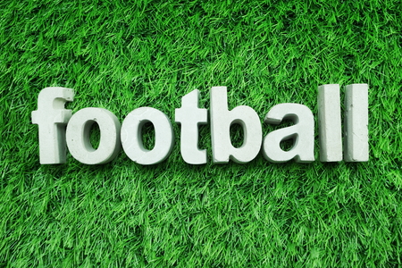 Football made from concrete alphabet top view on green grass